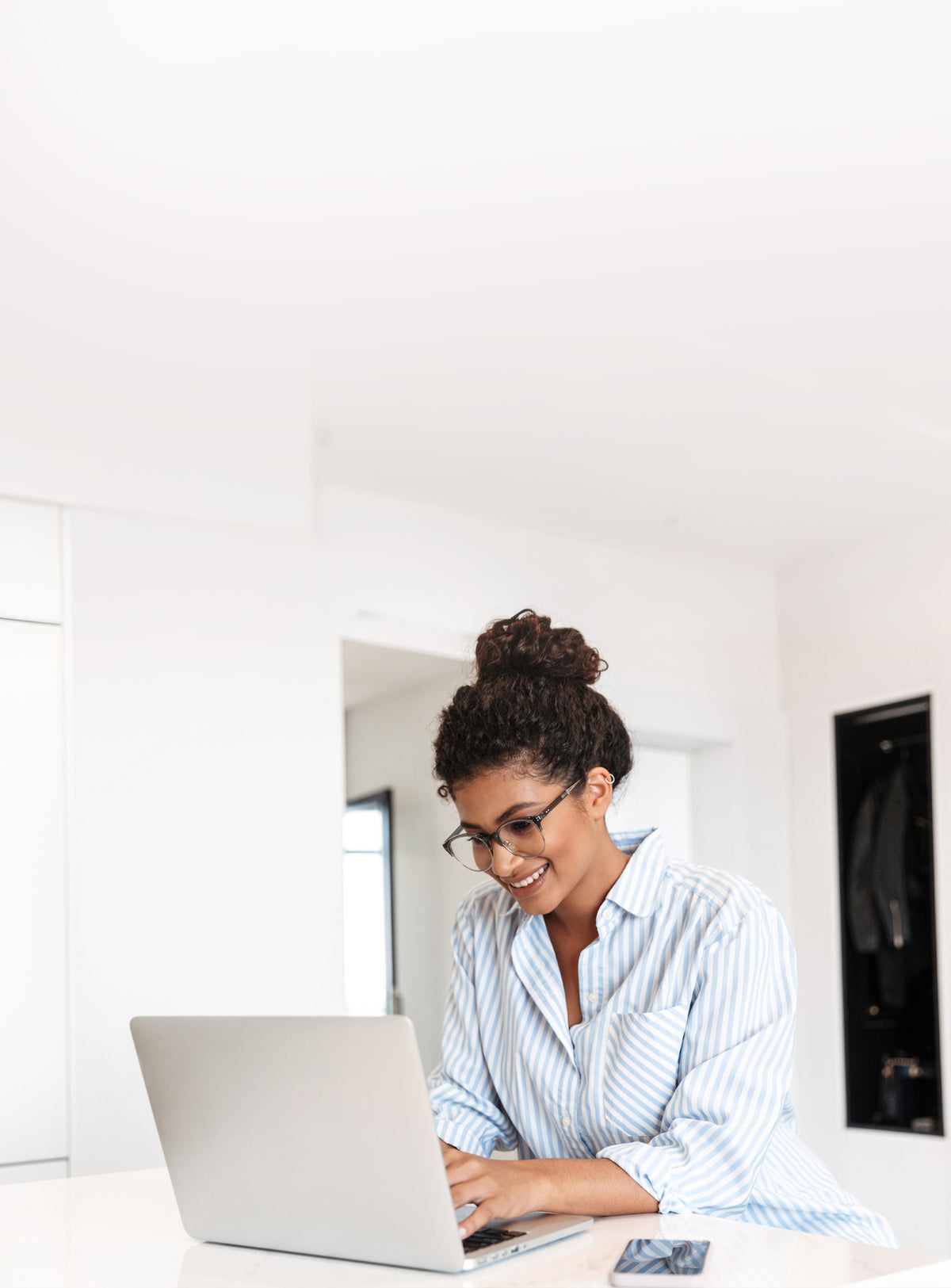 Lady on a laptop in a white kitchen