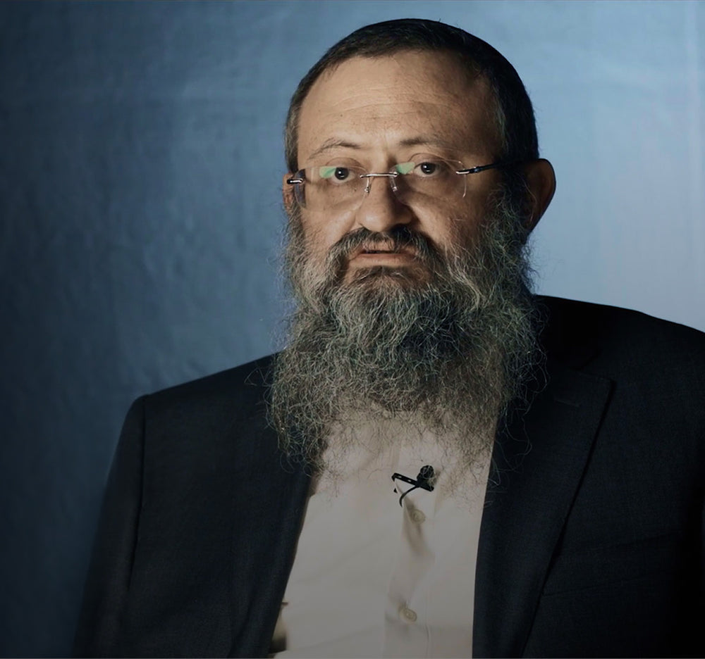 Doctor Zelenko, a man with a beard and glasses wearing a suit against a dark background
