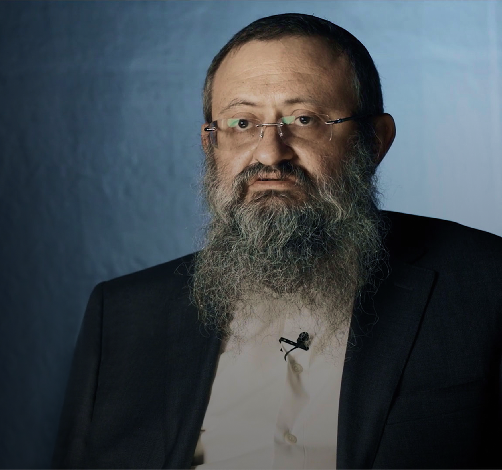 Doctor Zelenko, man with a long beard and glasses wearing a dark suit against a blue background